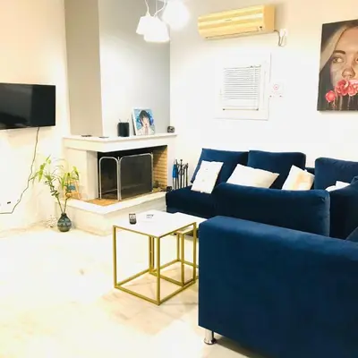 a living room with a blue couch and a fireplace at Beautiful maisonette with a view to the mountains and the sea in Aghia Marina