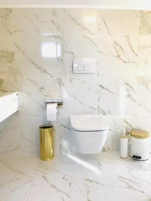 a white marble bathroom with a toilet in it at Beautiful maisonette with a view to the mountains and the sea in Aghia Marina