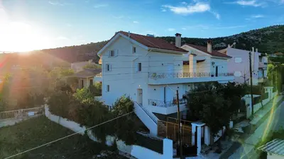 a large white house with the sun behind it at Beautiful maisonette with a view to the mountains and the sea in Aghia Marina