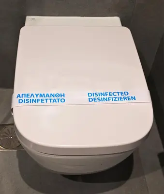 a white toilet with a sign on the side of it at Olvia Suites in Athens
