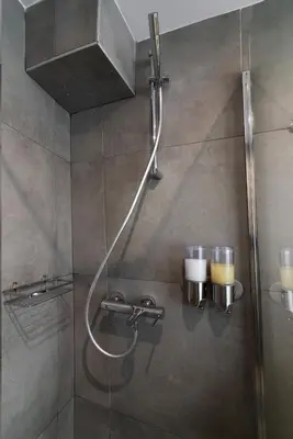 a shower in a bathroom with two candles on the wall at Olvia Suites in Athens