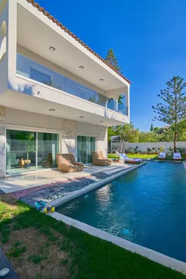a house with a swimming pool in front of a house at Luxury Villa with Pool, BBQ & Garden in Vouliagmeni in Athens