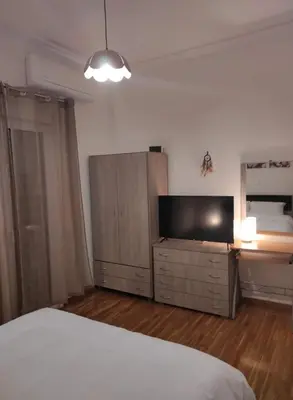 a bedroom with a bed and a flat screen tv at Lovely apartment next to Syggrou Fix metro station in Athens