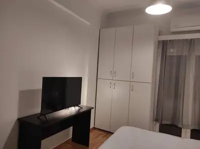 a bedroom with a bed and a desk with a television at Lovely apartment next to Syggrou Fix metro station in Athens