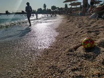 a person walking on a beach with a ball in the sand at Lovely apartment next to Syggrou Fix metro station in Athens