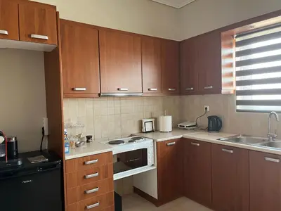 a kitchen with wooden cabinets and a stove top oven at ILION Air Host - near Athens International Airport in Markopoulo