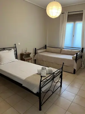 a bedroom with two beds and a chandelier at ILION Air Host - near Athens International Airport in Markopoulo