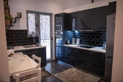 a kitchen with black tile walls and counters and a table at Sophia’s place in Piraeus