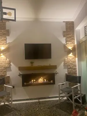 a living room with a fireplace with a tv on a wall at Sophia’s place in Piraeus