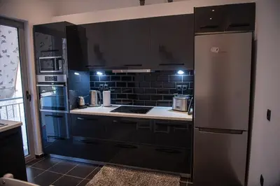 a kitchen with black cabinets and a refrigerator at Sophia’s place in Piraeus