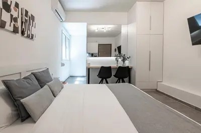 a bedroom with a large white bed and a kitchen at Phaedrus Living: City Center Executive Flat Stadiou in Athens