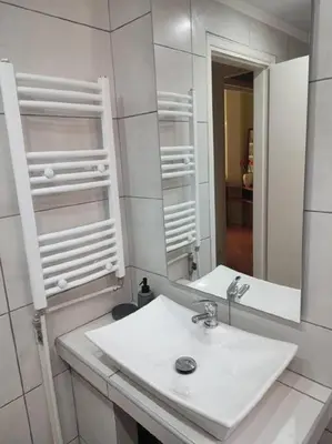 a white bathroom with a sink and a mirror at lovely penthouse at the center! in Athens