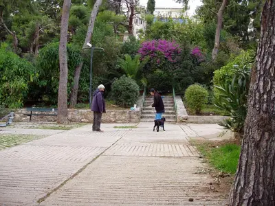 two people walking a dog on a sidewalk at PRIVATE BEDROOMS IN SHARED APARTMENT 135 SM ATHENS Center in Athens