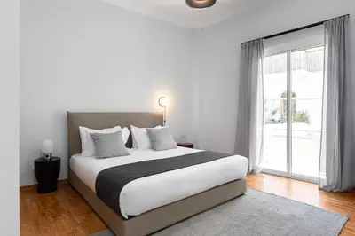 a white bedroom with a large bed and a window at KASO - Fotomara in Athens