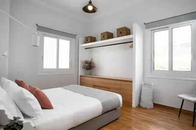 a white bedroom with a bed and two windows at KASO - Fotomara in Athens