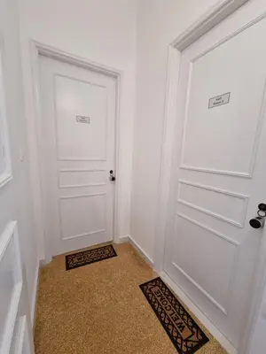 a hallway with two white doors and a rug at Hall Apartments & Rooms - by Avelink in Spáta