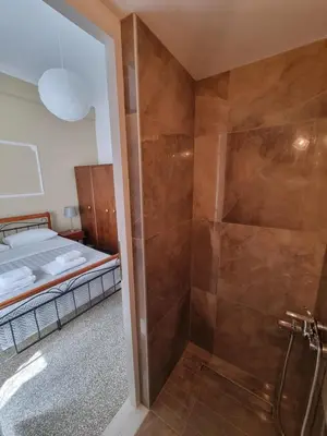 a bathroom with a walk in shower next to a bed at Hall Apartments & Rooms - by Avelink in Spáta