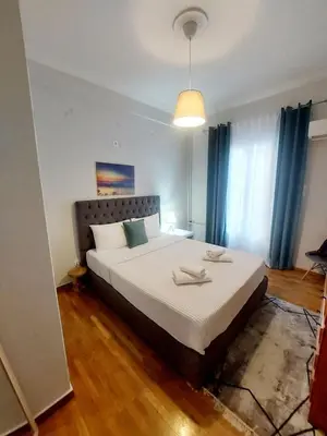 a bedroom with a large bed with blue curtains at Athens Apartment 1-min Walk to Kato Patissia Metro in Athens