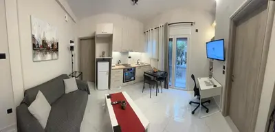 a living room with a couch and a table and a kitchen at Cozy flat in Hilton, central Athens, 3' metro, VFM! in Athens