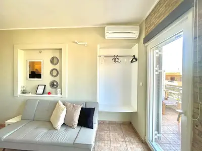 a living room with a couch and a window at Aggelou Apartments-10 min from Athens airport in Spáta