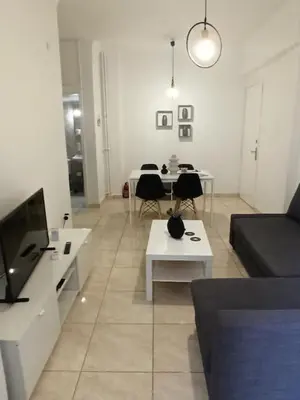 a living room with a couch and tables and a tv at Pagrati apartment Διαμέρισμα Παγκράτι in Athens