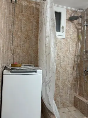a shower curtain in a bathroom with a refrigerator at Pagrati apartment Διαμέρισμα Παγκράτι in Athens