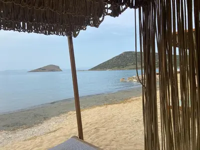 an umbrella sitting on a beach with the water at Architect's summer house by the beach in Porto Rafti