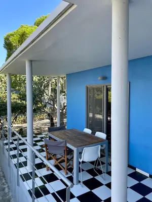 a patio with a table and chairs on a blue house at Architect's summer house by the beach in Porto Rafti