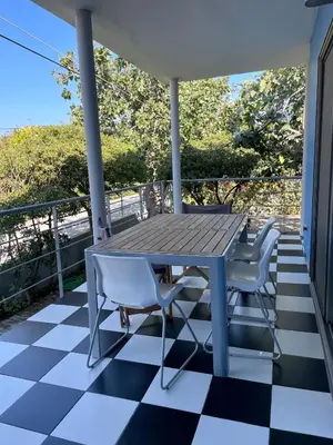 a table and chairs on a porch with a checkered floor at Architect's summer house by the beach in Porto Rafti