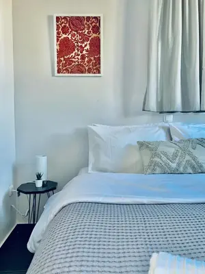 a bed with white sheets and a picture on the wall at Navitas House in Athens