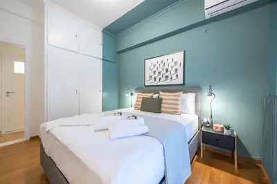 a bedroom with a large white bed with blue walls at City Suite by Cloudkeys in Athens