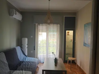 a living room with a couch and a table and a window at Evangelli Apartment- An oasis inside the center of Athens in Athens