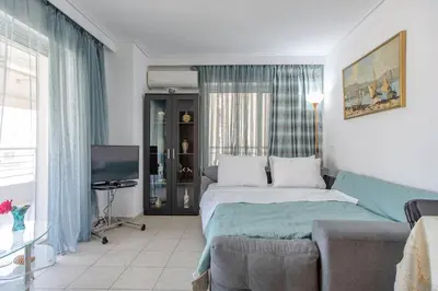 a bedroom with a bed and a couch and a tv at Flat w Parking at Flisvos Marina & SNFCC, 300mbps in Athens