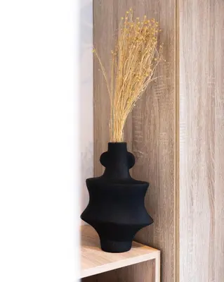 a black vase sitting on a shelf with a plant at PAME Wild in Athens