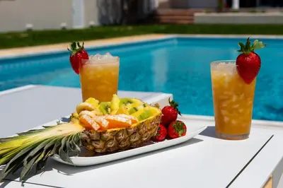a plate of food with a pineapple and two cocktails at Kamariyo Athens Riviera by A&D Properties in Palaiá Fókaia
