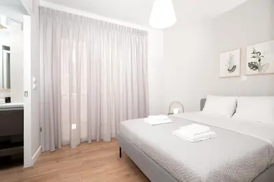 a white bedroom with a bed with two towels on it at Blue Avra Apartment by A&D Properties in Porto Rafti