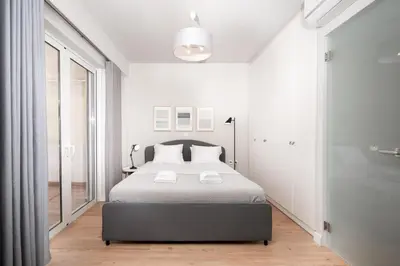 a bedroom with a bed and a large window at Blue Avra Apartment by A&D Properties in Porto Rafti