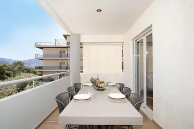 a white dining room with a table and chairs at Blue Avra Apartment by A&D Properties in Porto Rafti