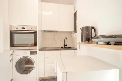 a white kitchen with a washing machine and a sink at Lovely studio 1' from Attiki metro station in Athens