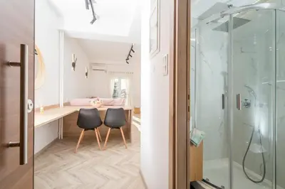 a bathroom with a glass shower and two black chairs at Lovely studio 1' from Attiki metro station in Athens