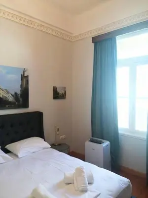 a bedroom with a bed with a blue curtain and a window at Elegant apartment under the Acropolis in Athens