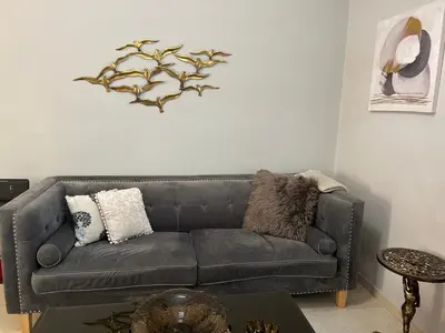a leather couch in a living room with a branch on the wall at ZEN Neapoli Penthouse Apartment in Athens