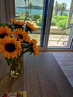 a vase filled with orange flowers sitting on a table at Seaview-Apartments in Palaiá Fókaia