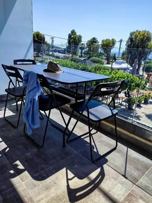a picnic table with chairs and a hat on it at Seaview-Apartments in Palaiá Fókaia