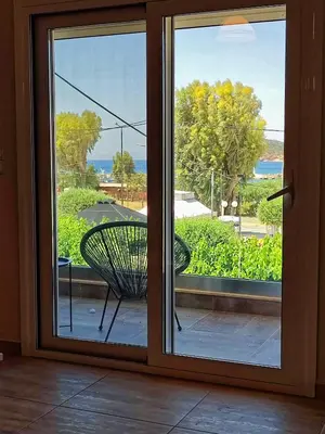 a sliding glass door with a chair on a balcony at Seaview-Apartments in Palaiá Fókaia
