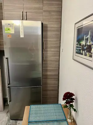 a stainless steel refrigerator in a kitchen with a table at New apartment at Athenian Riviera in Athens