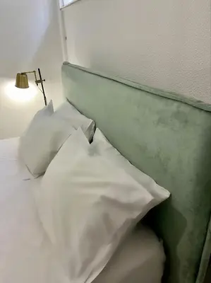 a bed with white sheets and pillows next to a lamp at New apartment at Athenian Riviera in Athens