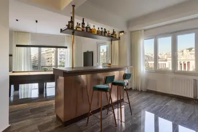 a bar with green stools in a room with a piano at A Truly WOW Experience for Every Guest. THE place in Athens