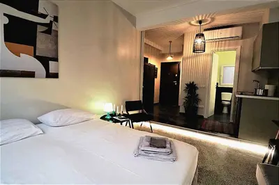 a bedroom with a white bed and a living room at Central urban studio B in Athens