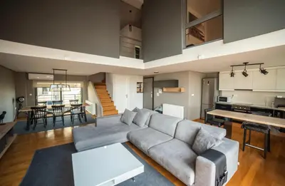 a living room with a gray couch and a kitchen at Minimal New Loft next to Subway in Athens